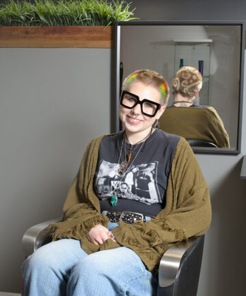 Portrait of Locke Hair stylist Ava, sitting in a chair in the salon.